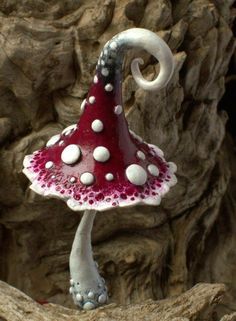 a red and white mushroom sitting on top of a rock