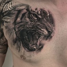 a man's chest with a tiger tattoo on it and his face painted in black ink