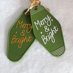 two green tags with merry and bright written on them are hanging from a gold chain