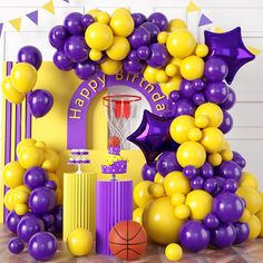 purple and yellow balloon arch with basketballs, stars, and hoop on the floor