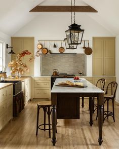 a kitchen with an island and wooden chairs in the center, along with hanging lights