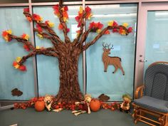 an office cubicle decorated with fall leaves and paper mache animals, including a tree