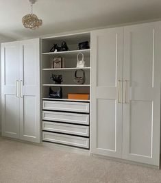 a white closet with drawers and shoes on the bottom shelf in front of it is a chandelier