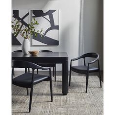 a black table with two chairs and a vase on it in front of a painting