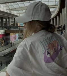 a woman in a white shirt and hat looking at the glass floor inside a building