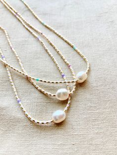 Thin beaded necklace with rice pearl. This necklace is made with high quality Japanese seed beads that are perfect cylinders. Necklace clasp and jump rings are gold plated. Natural silk cord with frayed tassel ends. Available with a hint of color in sea green, rose and wisteria 15.5 inches long. Add a Chain Extender for adjustable length: https://etsy.me/34lPf3m ✨ FREE SHIPPING IN THE USA ✨ 🌎 Packaging 🌎 To be environmentally responsible about packaging we will package orders together in the s Delicate Choker Necklace, Necklace With Pearls, Delicate Choker, Gold Beaded Necklace, Necklace With Pearl, Minimalist Necklace Gold, Tiny Necklace, Necklace Clasp, Diy Jewelry Necklace