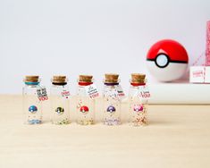 six bottles with different designs are lined up on a table next to a pokeball