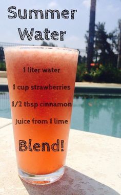 a glass filled with liquid sitting on top of a table next to a swimming pool