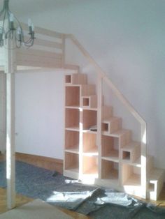 a room that has some shelves under the stairs and a chandelier hanging from the ceiling