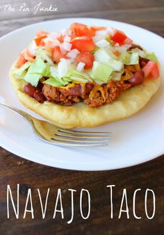 a taco sitting on top of a white plate with a fork next to it