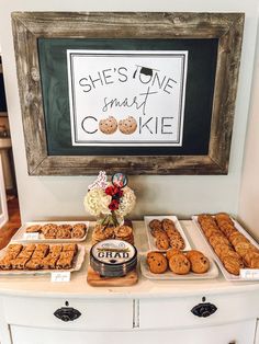 a table topped with lots of cookies next to a framed sign that says she's one smart cookie