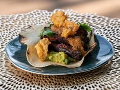 a taco filled with meat and vegetables sitting on top of a blue plate