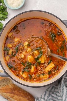 a bowl filled with soup next to bread and parsley on the side, along with other food items