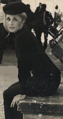 a black and white photo of a woman sitting on steps with her suitcase in hand