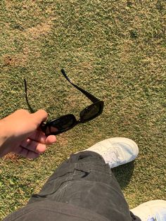 a person holding onto some black sunglasses on the grass