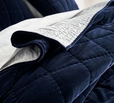 an unmade bed with blue and white comforter on it's side, next to a pillow