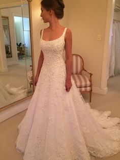 a woman standing in front of a mirror wearing a white wedding dress with lace on it