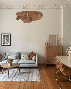 a living room filled with furniture and a white couch next to a wooden table on top of a hard wood floor