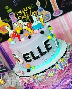 a birthday cake with the word elif on it and some decorations around it for a science themed party