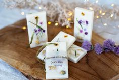 four soap bars with flowers on them sitting on a wooden board next to some lights