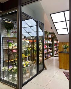 the inside of a flower shop with lots of flowers on display in glass doors and shelves