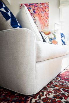 a white couch sitting on top of a colorful rug