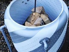 a large blue bucket filled with wood on top of gravel