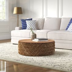 a living room with white couches and blue pillows on the floor, along with a coffee table