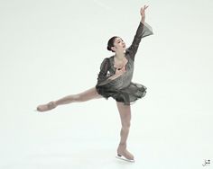 a woman in a black and silver dress is doing a ballet move with her arms outstretched