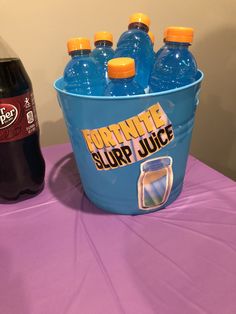 several bottles of soda sit on a table next to a plastic bucket with liquid in it