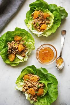 three lettuce cups filled with meat and vegetables next to a jar of sauce