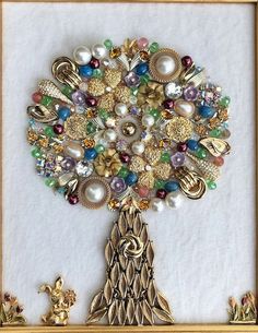 a tree made out of beads and other items in a gold frame on a white surface