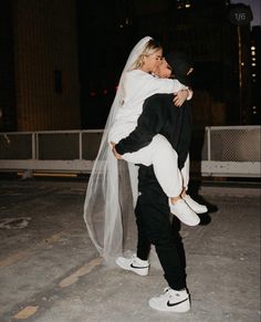 a man carrying a woman on his back in the street at night with buildings in the background