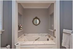 a bath tub sitting inside of a bathroom next to a mirror on the side of a wall