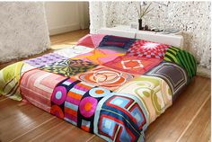 a bed covered in colorful quilts on top of a wooden floor