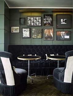 two black velvet chairs sitting next to each other in front of pictures on the wall