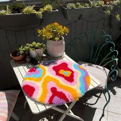 a multicolored rug sitting on top of a table next to potted plants