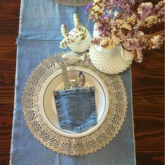 a place setting with blue napkins and silverware on a lace doily next to flowers