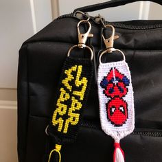 two keychains are attached to a black bag with yellow and red letters on it