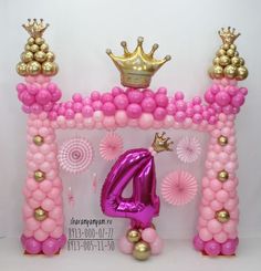 a pink and gold balloon arch with a crown on top