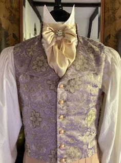 Mens single breasted Regency style waistcoat made in an opulent lilac, gold and silver brocade in an eye catching floral design, six gold tone filigree buttons, stand collar with shaped lapels. The sumptuous fabric is a lavish lilac, gold and silver brocade in an eye catching floral design, the metallic threads catch the light wonderfully, the fabric is absolutely perfect for the Regency period. It will look stunning for a Regency Ball, Bridgerton Event, Regency Wedding, The Jane Austen Festival. Six unusual filigree gold tone buttons to the front of the waistcoat, which add that extra luxurious period detail and also catch the light beautifully. The waistcoat is backed in a ivory coloured medium weight cotton. The waistcoat is fully lined in antique gold satin. The chest will fit up to 38 Elegant Wedding Vest With Buttons, Elegant Gold Nehru Jacket For Formal Occasions, Fitted Wedding Vest With Buttons, Fitted Vest With Buttons For Wedding, Fitted Gold Vest Elegant Style, Elegant Gold Fitted Vest, Gold Fitted Vest, Fitted Gold Elegant Vest, Elegant Sleeveless Gold Vest