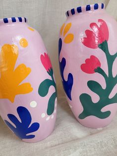 two pink vases with colorful flowers painted on them