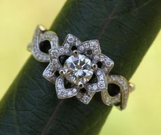 a diamond ring sitting on top of a green piece of leaf with diamonds around it