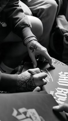 a person with tattoos on their arm and wrist is signing autographs for someone else