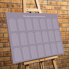 a wooden easer with a seating chart on it in front of a brick wall