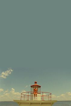 a man standing on top of a pier next to the ocean under a cloudy blue sky