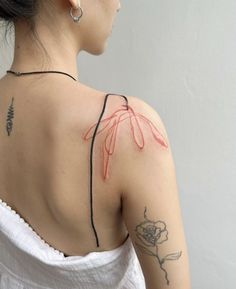 the back of a woman's shoulder with tattoos on it