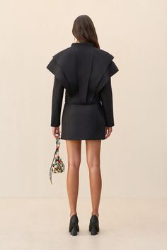 A v neck wool blend jacket with exaggerated layered shoulder design and wrap waist that can be worn as an off-the-shoulder top. — V neck — Long sleeve — Layered shoulder — Wrap waist closure — Wear with the Angelia Skirt for a matching set Chic Structured Party Outerwear, Chic Outerwear With Structured Shoulders For Party, Black Outerwear With Structured Shoulders For Evening, Black Evening Outerwear With Structured Shoulders, Evening Outerwear With Structured Shoulders, Black Blazer With Structured Shoulders, Black Structured Shoulder Blazer For Fall, Chic Black Blazer With Structured Shoulders, Black Blazer With Structured Shoulders For Fall