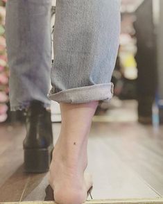 a woman's legs and feet with high heeled shoes on top of a wooden floor