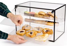 a man is picking up pastries from a display case on a white background,